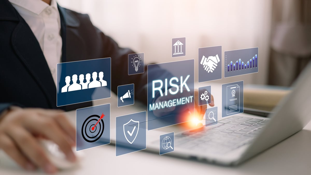 A businessman analyzes a virtual risk management interface with critical strategy icons on a laptop screen. Corporate risk management strategy concept.