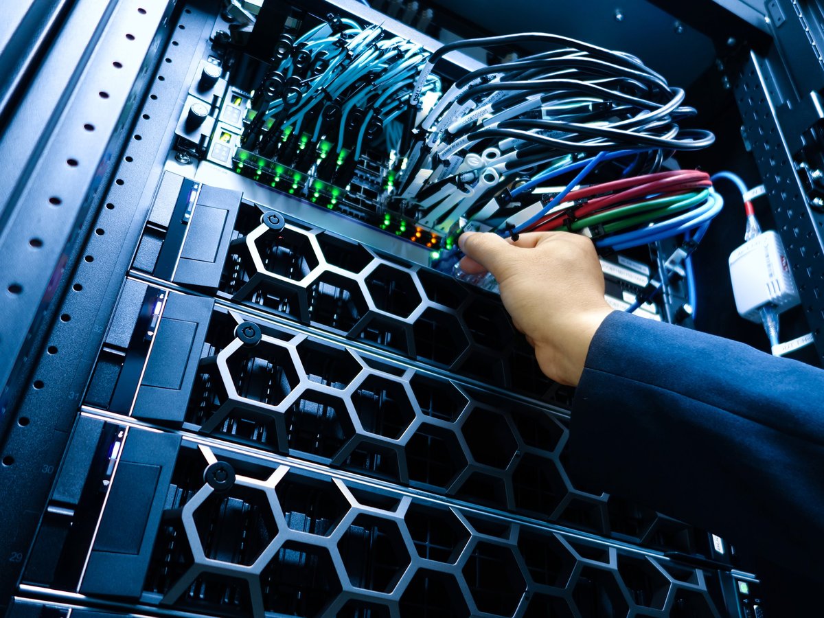 A technician performs maintenance on a server rack, managing cables and hardware for optimal performance and connectivity in a modern data center environment