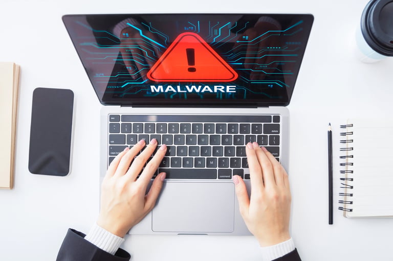Hands typing on laptop with malware alert graphic, concept of cyber threat and digital security