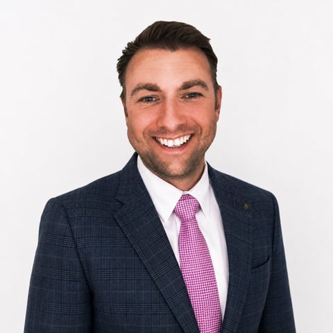 Professional headshot of Wayne Jenkinson, Commercial Director of Contrac, smiling wearing a dark navy plaid blazer and pink gingham tie